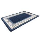 A rectangular carpet, the blue field with fleur-de-lys spandrels, within scrolling foliate