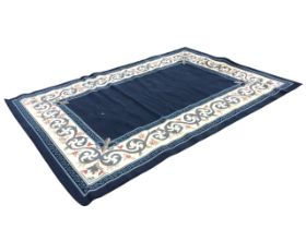 A rectangular carpet, the blue field with fleur-de-lys spandrels, within scrolling foliate