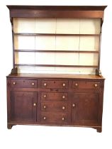 A Georgian oak dresser, the delft rack with moulded cornice and painted boarded back above three