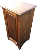 An Edwardian mahogany bedside cabinet, the rectangular moulded top above a door with arched