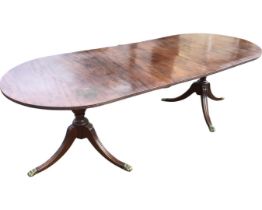 A Georgian style twin pedestal mahogany dining table, the rounded rectangular top with ribbed edge