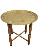A circular brass coffee table with foliate embossed decoration to tray top bordered by crimped