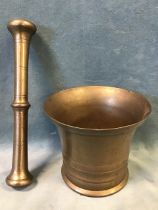 An antique bronze pestle and mortar, the mortar with cylindrical turned body and flared rim, the