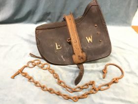 A leather draught horse saddle and chain, the leather cover with wood and iron frame having brass