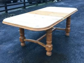 A pine extending dining table, the rounded rectangular moulded top with spare leaf raised on