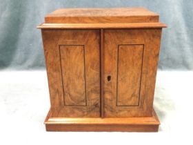 A Victorian walnut cabinet with boxwood & ebony strung panelled doors enclosing three velvet lined
