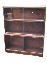 A mid-century mahogany bookcase, the rectangular top above shelves with sliding glass doors, the