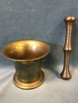 An antique bronze pestle and mortar, the flared body on a circular base, with a double-ended pestle.