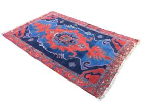 A Turkey rug woven with central floral medallion on red field within a hooked blue & black border,