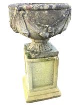 A composition stone urn on stand, the bowl with leaf moulded swagged decoration on fluted socle,