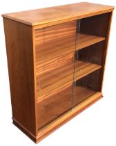 A teak bookcase, the rectangular moulded top above two sliding glass doors enclosing adjustable