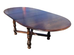 An Ercol elm Old Colonial pattern extending dining table, the top with an spare leaf, raised on