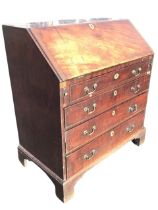 A Georgian mahogany bureau, the slant front with baize lined writing surface opening on lopers to