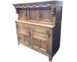 An eighteenth century oak court cupboard with later alterations, the bog oak & holly inlaid frieze