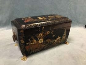 A Regency japanned sarcophagus shaped tea caddy with brass ring handles, decorated with