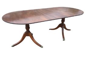 A Georgian style mahogany extending twin pedestal dining table, the crossbanded top with reeded edge