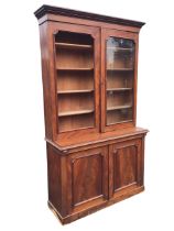 A Victorian mahogany bookcase cabinet, the moulded cornice above a pair of rounded glass doors