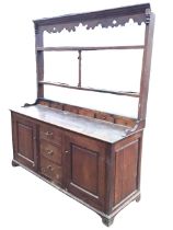 A C19th oak dresser, the open delft rack with moulded cornice above a shaped apron and three shelves