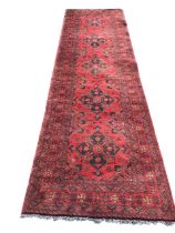 A bokarra wool runner woven with five quatrefoil medallions on red field framed by multiple floral