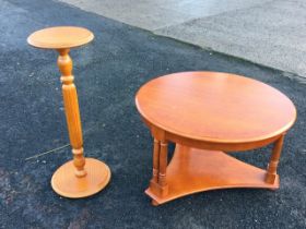 A circular crossbanded teak coffee table raised on paired column legs joined by a concave triangular