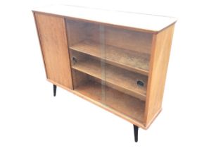 A 60s teak cabinet with shaped top above sliding glass and single door, raised on ebonised