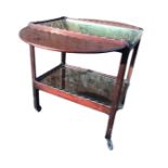 A mahogany supper table with rounded drop-leaves, the tray top trolley with two scalloped shelves