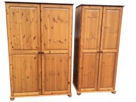 A pine double wardrobe with fielded panelled knobbed doors enclosing a shelf above hanging space,