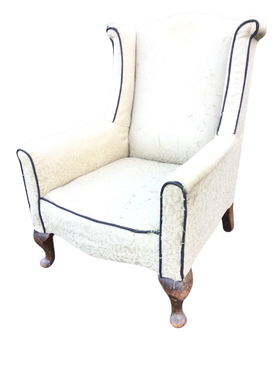An Edwardian upholstered wing armchair, the arched back and outscrolled wings above a bowfronted