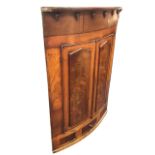 A nineteenth century mahogany bowfronted corner cabinet with rosewood banding, the frieze with