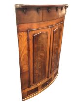 A nineteenth century mahogany bowfronted corner cabinet with rosewood banding, the frieze with