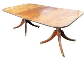An Edwardian mahogany regency style twin pedestal dining table with spare leaf, the rounded