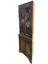 A stained deal Jacobean style corner cabinet, the moulded cornice above a carved frieze and two