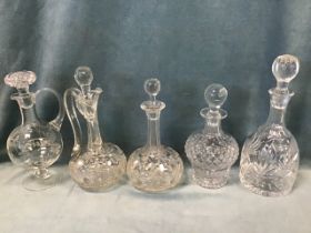 An engraved claret jug with ball stopper; three miscellaneous cut glass decanters & stoppers; and