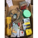 Box of fishing related items, including hooks, a net, a reel, books, etc