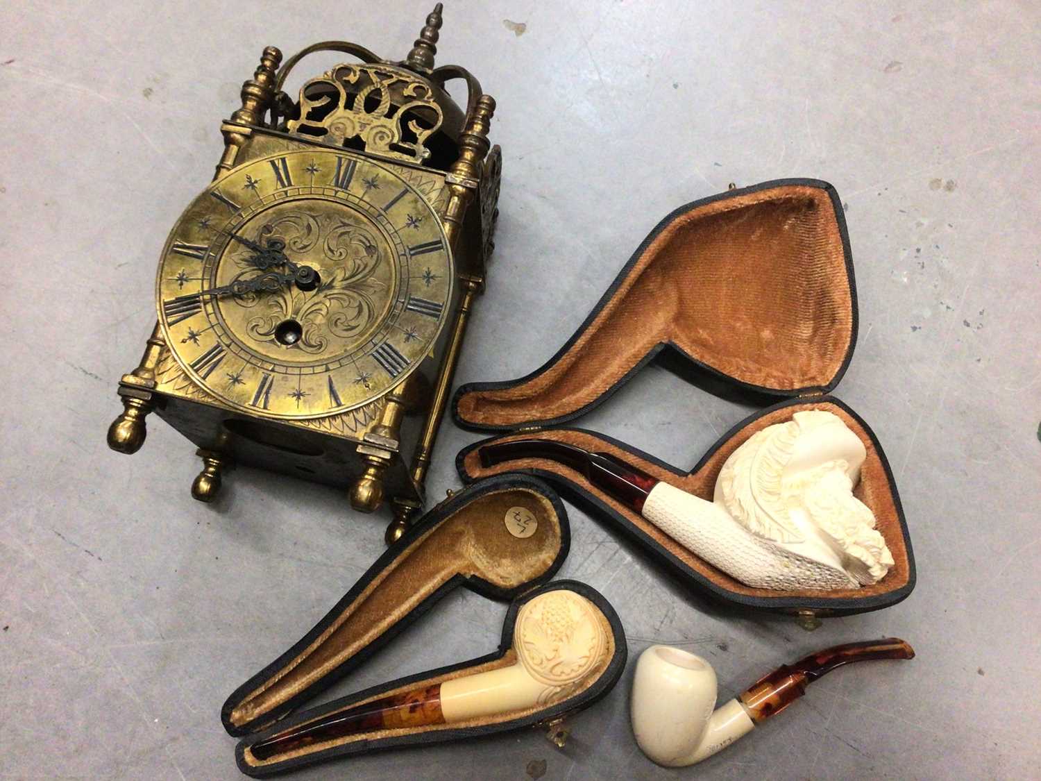 Three cased meerschaum pipes, together with a 17th century style brass lantern clock