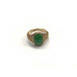 18ct gold green hard stone oval panel ring with carved floral scroll shoulders, size M