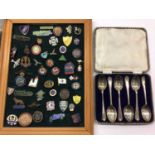 Set of six silver golfing spoons in fitted case and a collection of enamelled badges mounted on a fr