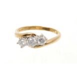 Diamond three stone ring with three brilliant cut diamonds in cross-over claw setting on 18ct yellow