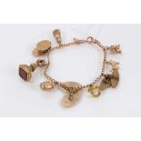 9ct gold charm bracelet with various 9ct gold charms including a yellow metal seal fob and a gold pl