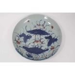 A 19th century Chinese porcelain charger, painted in underglaze blue and red with lotus flowers