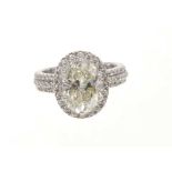 Diamond halo cluster ring with an oval mixed-cut diamond weighing approximately 3cts, surrounded by