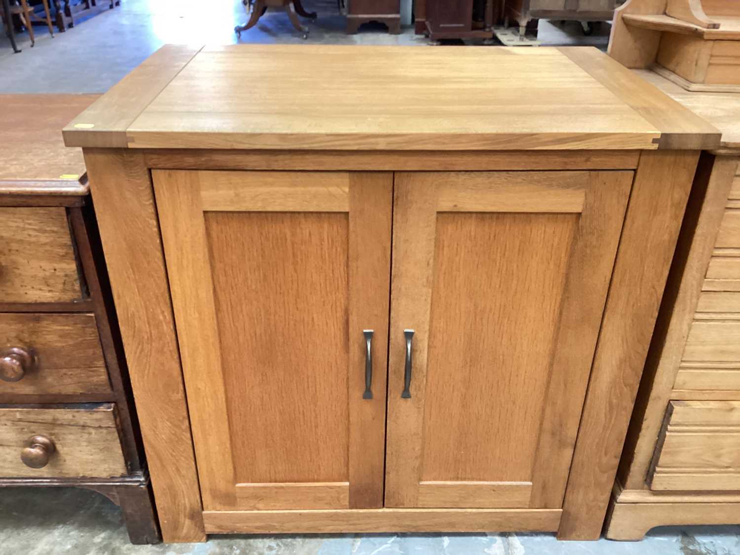 Contemporary light oak cupboard with shelved interior enclosed by a pair of panelled doors.