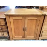 Contemporary light oak cupboard with shelved interior enclosed by a pair of panelled doors.