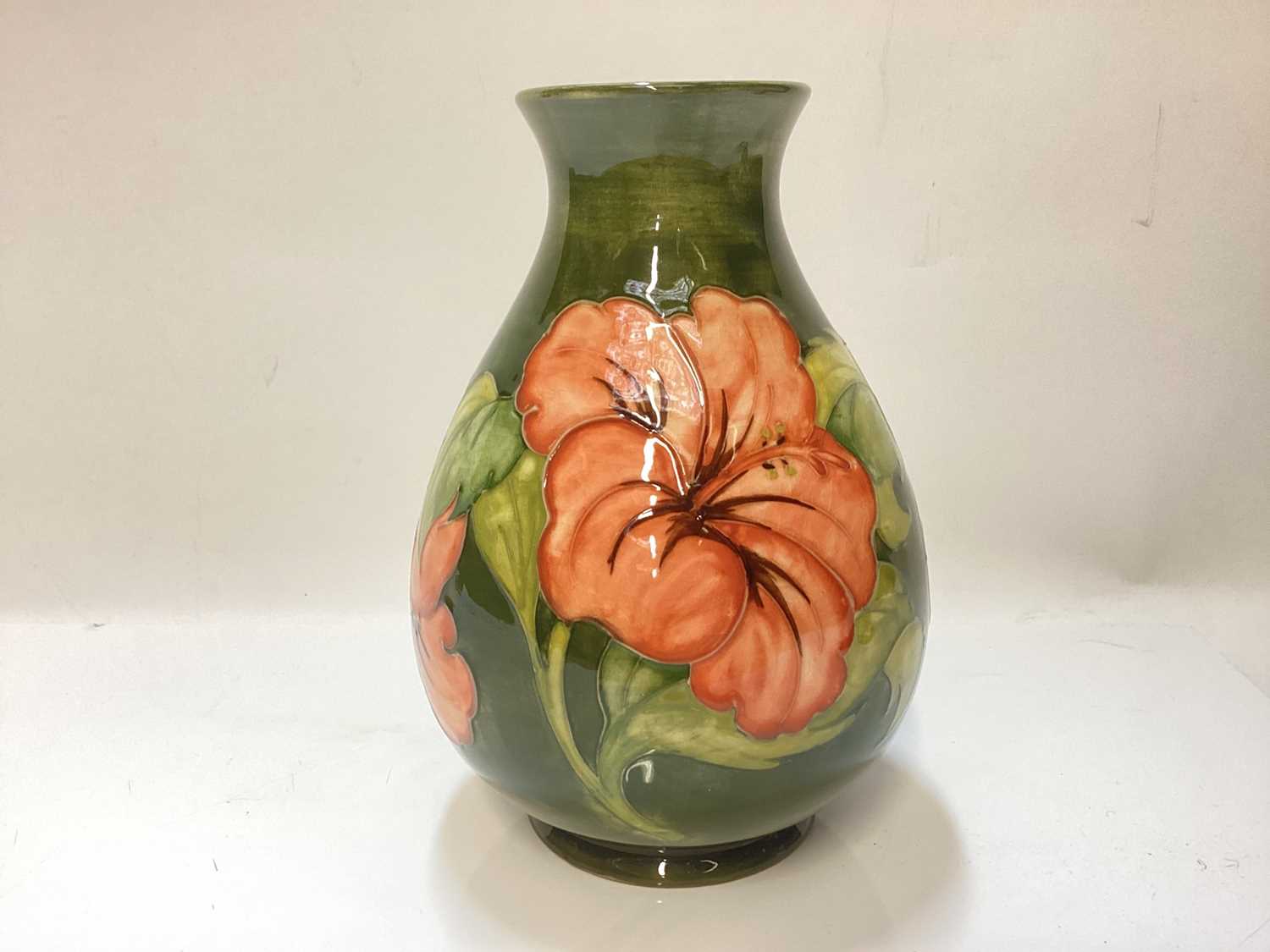 Moorcroft pottery vase decorated in the Hibiscus pattern on green ground, impressed marks to base, a