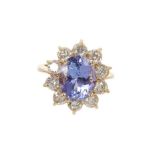 Tanzanite and diamond cluster ring with an oval mixed cut tanzanite measuring approximately 10.8mm x