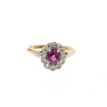 Ruby and diamond cluster ring with an oval mixed cut ruby surrounded by a border of single cut diamo
