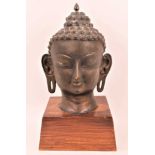 Large Tibetan bronze head of buddha on a wooden base