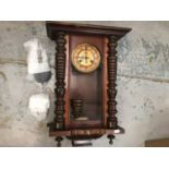 A wooden cased wall clock with pendulum and key