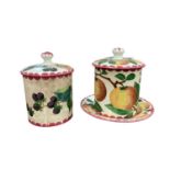 Two Wemyss pottery lidded jars together a dish, all decorated with fruit