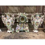 Continental porcelain clock garniture, with figural and floral decoration, enamel dial, 35cm high